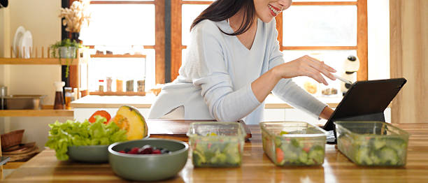 istock woman using digital tablet for recipe guidance while preparing healthy meals on kitchen counter. 2240068181
