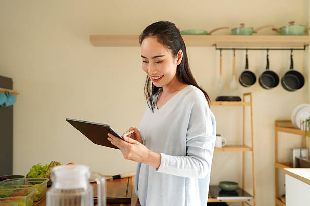 istock Woman organizing kitchen containers while using a tablet for meal planning on counter. 2240068199