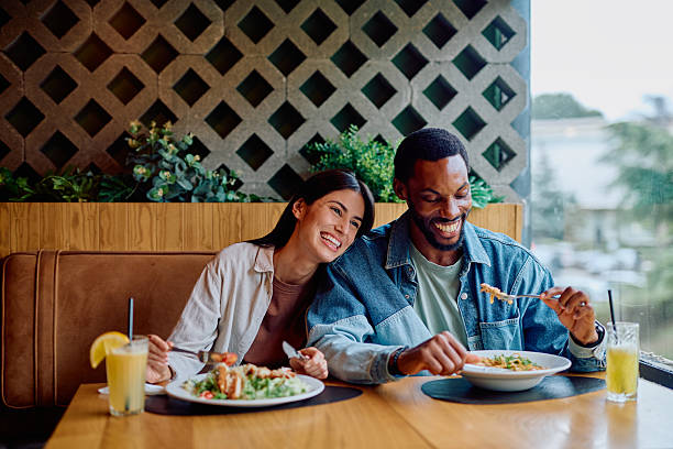 istock Diverse couple laughing eating meal in restaurant 2240069296