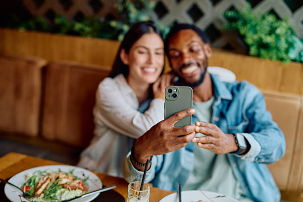 istock Interracial couple taking selfie with smartphone in restaurant 2240069399