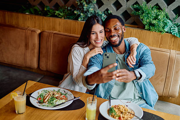 istock Interracial couple smiling, taking selfie during restaurant date 2240069400