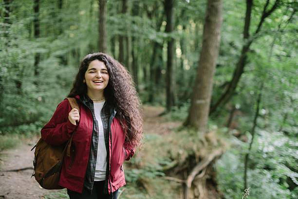 istock Young woman smiling while hiking in forest 2240070102