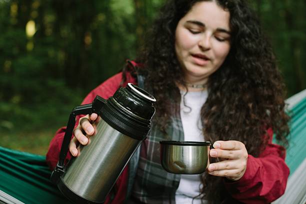 istock Young woman pouring warm drink on hammocking break 2240070177