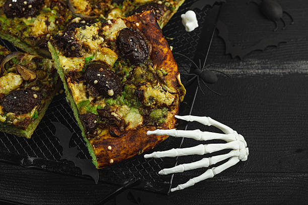 Spooky homemade pizza with green dough, mushroom skulls, and melted cheese. Halloween dark food