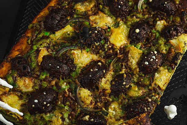 Spooky homemade pizza with green dough, mushroom skulls, and melted cheese. Halloween dark food