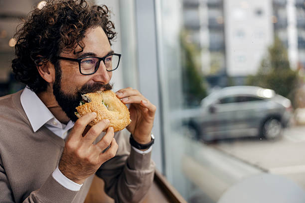 istock Man enjoying snack in cafe, looking out window 2240073169