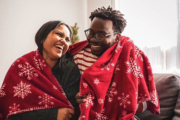 istock Diverse couple laughing wrapped in cozy christmas blanket 2240073176