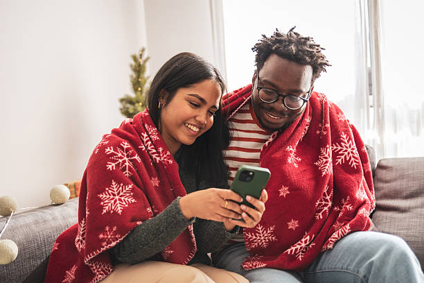 istock Diverse couple using smartphone on sofa during christmas holidays 2240073189