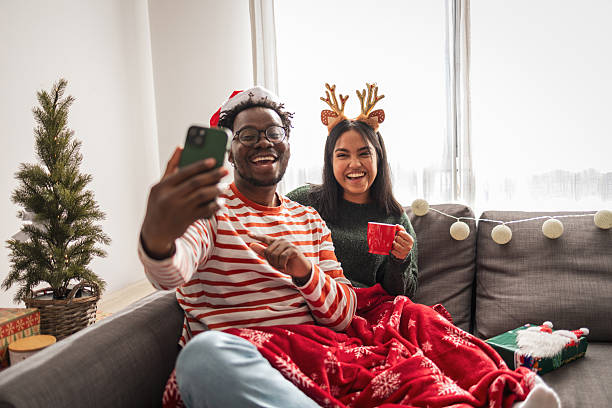 istock Diverse couple taking christmas selfie on cozy sofa 2240073210