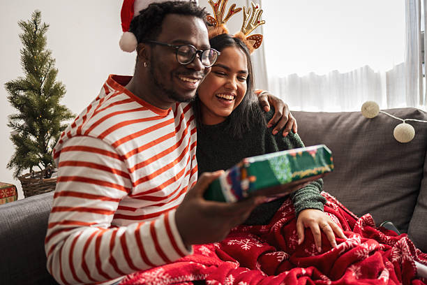 istock Diverse couple exchanging christmas gift at home smiling 2240073252