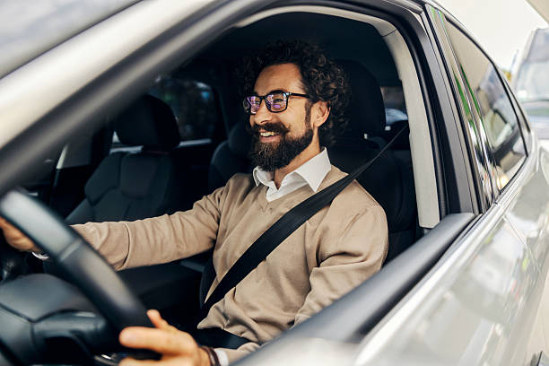istock Man smiling while driving car wearing seatbelt 2240073323
