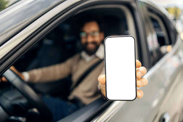 istock Man in car showing smartphone with blank screen 2240073356