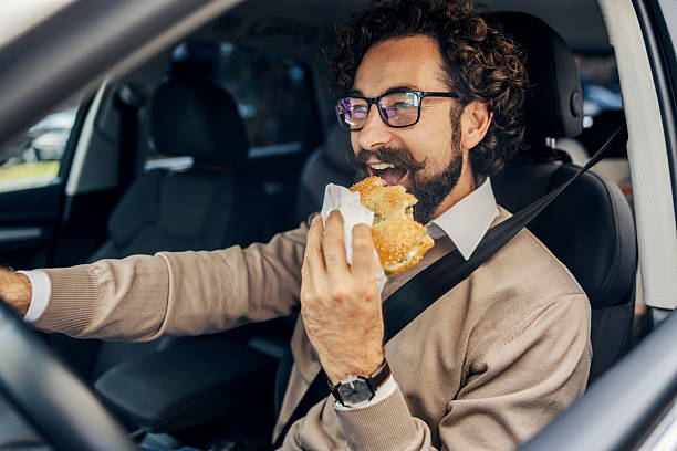 istock Busy man eating fast food sandwich while driving car 2240073372