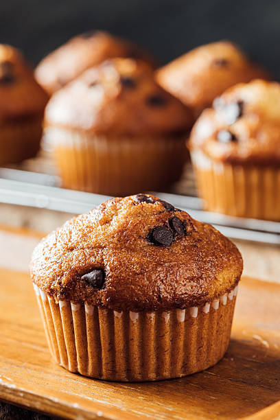 Freshly Baked Chocolate Chip Muffin on Wooden Board with Background