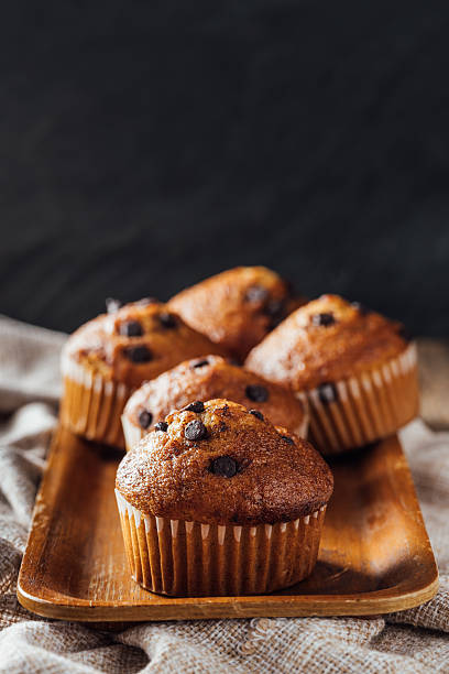 istock Freshly Baked Muffins with Chocolate Chips on Wooden Tray 2240075738