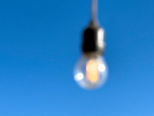 Minimal abstract image showing a blurred light bulb suspended in daylight.