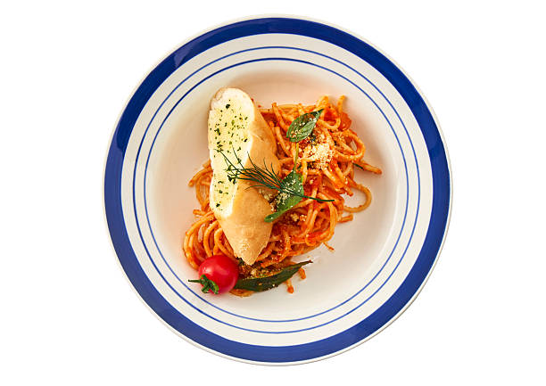 Woman hand holding a plate of spaghetti on a green wall.