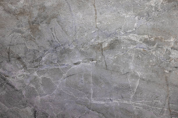 Close-up of a weathered gray stone wall showing cracks, veins, and natural texture. Suitable for backgrounds, architectural themes, and texture overlays in design projects.