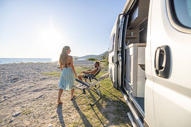 istock Couple Relaxing by Camper Van on Beach 2240078950