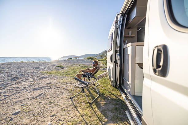 istock Man Relaxing by Camper Van on Beach 2240078976