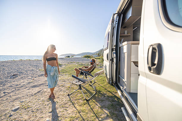 istock Couple Relaxing by Camper Van on Beach 2240078979