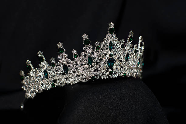 istock Crown with emerald green gemstones on black background. Jewelry 2240078984