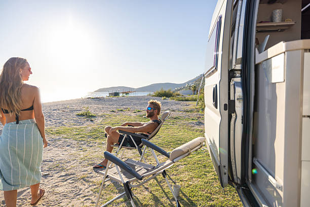 istock Couple Relaxing by Camper Van on Beach 2240079037