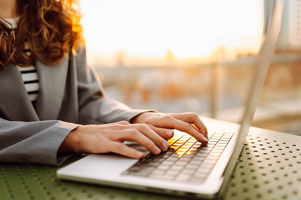 istock A close-up of a young woman's hands typing on a laptop while sitting at sunset. 2240080942