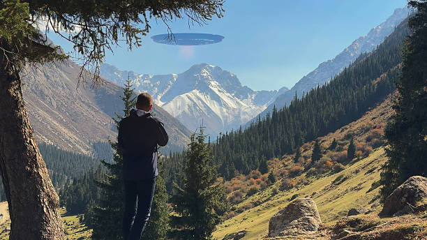 istock A lone tourist films an unidentified flying object hovering above a forested mountain valley. 2240082772