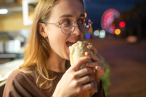 istock Young woman eating shawarma in the evening 2240084640