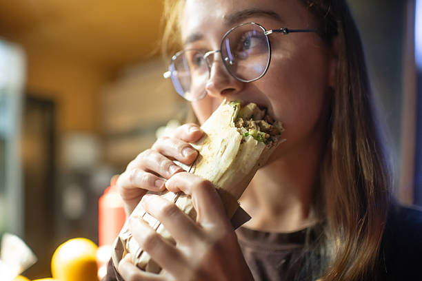 istock Young woman eating shawarma in the evening 2240084683