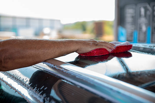 Close up male hand washing a car with soft sponge and soap foam