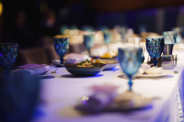 A beautifully arranged dinner table is decorated with elegant glassware and gourmet dishes in the center. The setting is perfect for a festive evening with guests, illuminated softly.