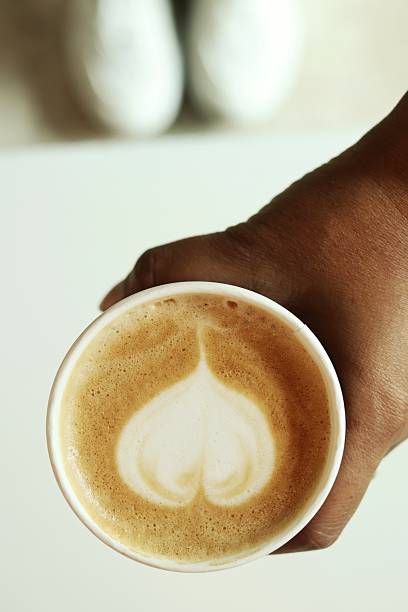 Heart latte art in coffee cup on hand