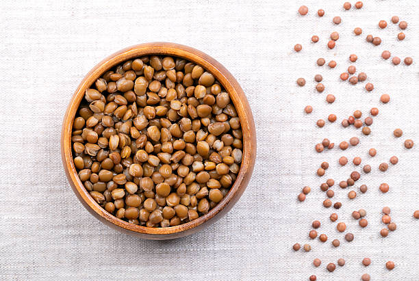 istock Cooked brown lentils, in a wooden bowl, on linen 2240090511
