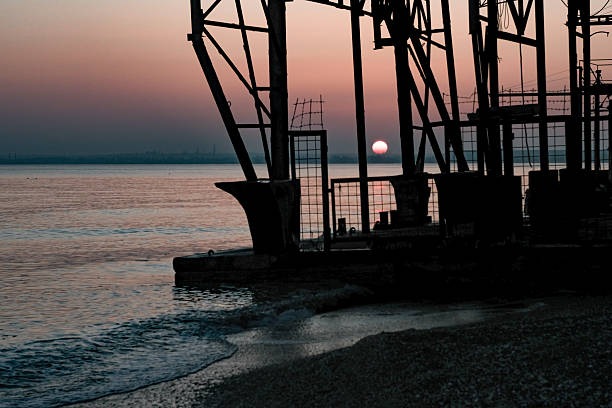 View of the sunset on the seashore through metal structures