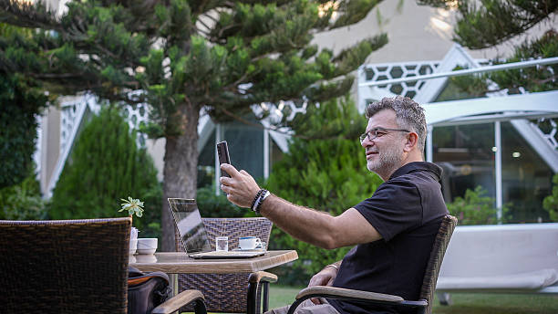 istock A middle-aged businessman is sitting in a hotel cafe taking a selfie.. 2240092292