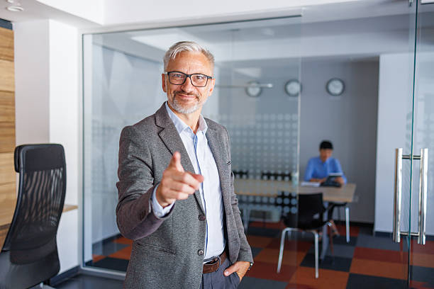 istock Confident mature businessman pointing finger at viewer in modern office 2240093045
