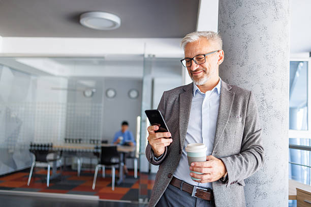 istock Mature businessman checking mobile phone during coffee break 2240093046