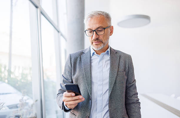 istock Mature businessman checking mobile phone in modern office environment 2240093085
