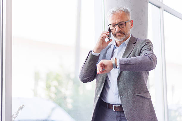 istock Mature businessman talking on phone and checking time 2240093095