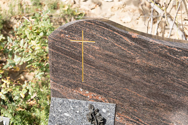 A grave in a cemetery with a Cross on a brown beige marble slab