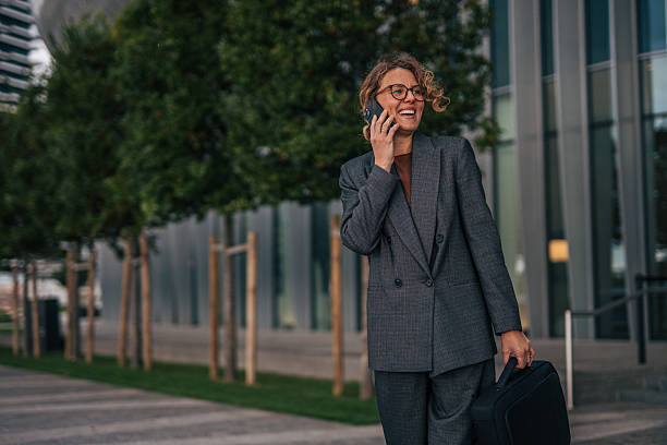 istock Businesswoman talking on phone outdoors carrying briefcase 2240095709