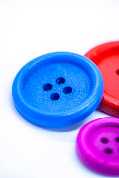 buttons on white surface, very soft focus with focus on the holes of the blue button
