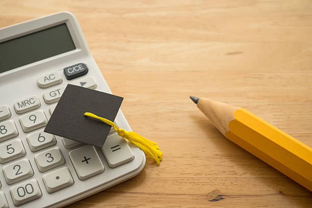 istock Graduation cap, white calculator and pencil on table. 2240096634