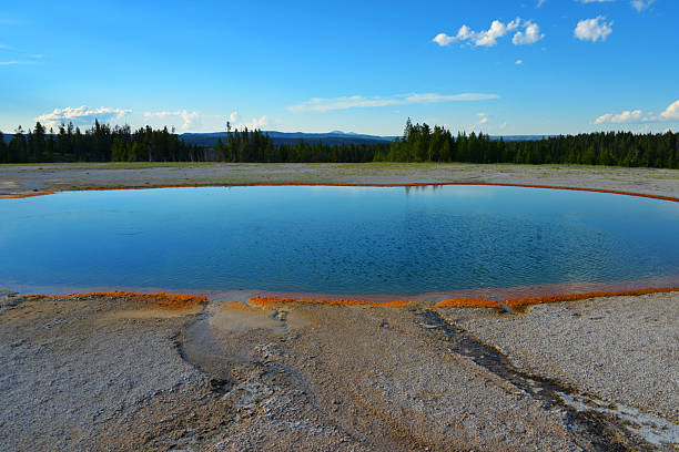 Yellowstone National Park, Wyoming, United States:Turquoise Pool is a notable hot spring located in the Midway Geyser Basin. Named by the Hayden Expedition of 1878, its turquoise color is a result of light scattering in the deep, clear water, which is heated to temperatures between 142 and 160°F (61 and 71°C). The pool's water drains partly through seepage, with some overflow and is known to have an underground connection to the nearby Excelsior Geyser. While often overshadowed by its larger neighbors, Grand Prismatic Spring and Excelsior Geyser, Turquoise Pool is a significant geothermal feature in the basin, appreciated for its intense coloration and relatively tranquil appearance.