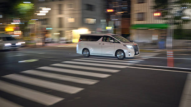 Tokyo, Japan - October 9, 2025:  A panning photo of a van driving at night in the Koto Ward of Tokyo, Japan.