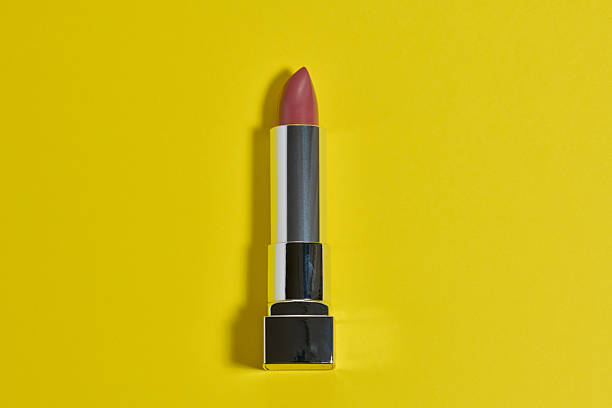 istock Fuchsia lipstick in a stylish metallic silver case. The lipstick is positioned against a bright yellow background 2240105069
