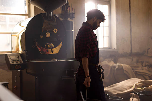 istock Barista Working Beside Coffee Roasting Machine in Sunlit Vintage Workshop 2240106037