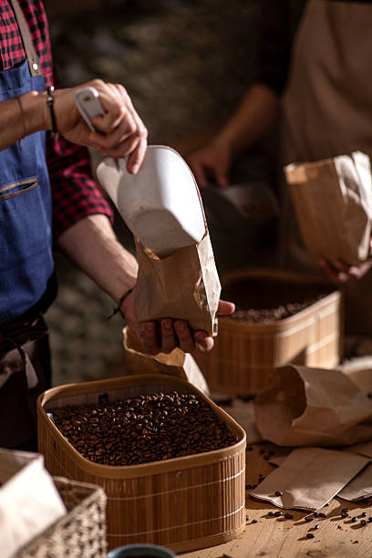 istock Coffee Beans Being Packed Into Paper Bags by Artisan Hands 2240106095